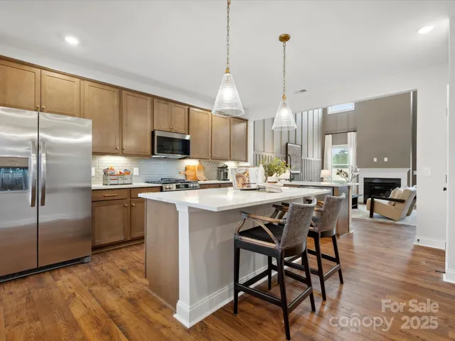 a kitchen with stainless steel appliances granite countertop a refrigerator a stove a sink a dining table and chairs