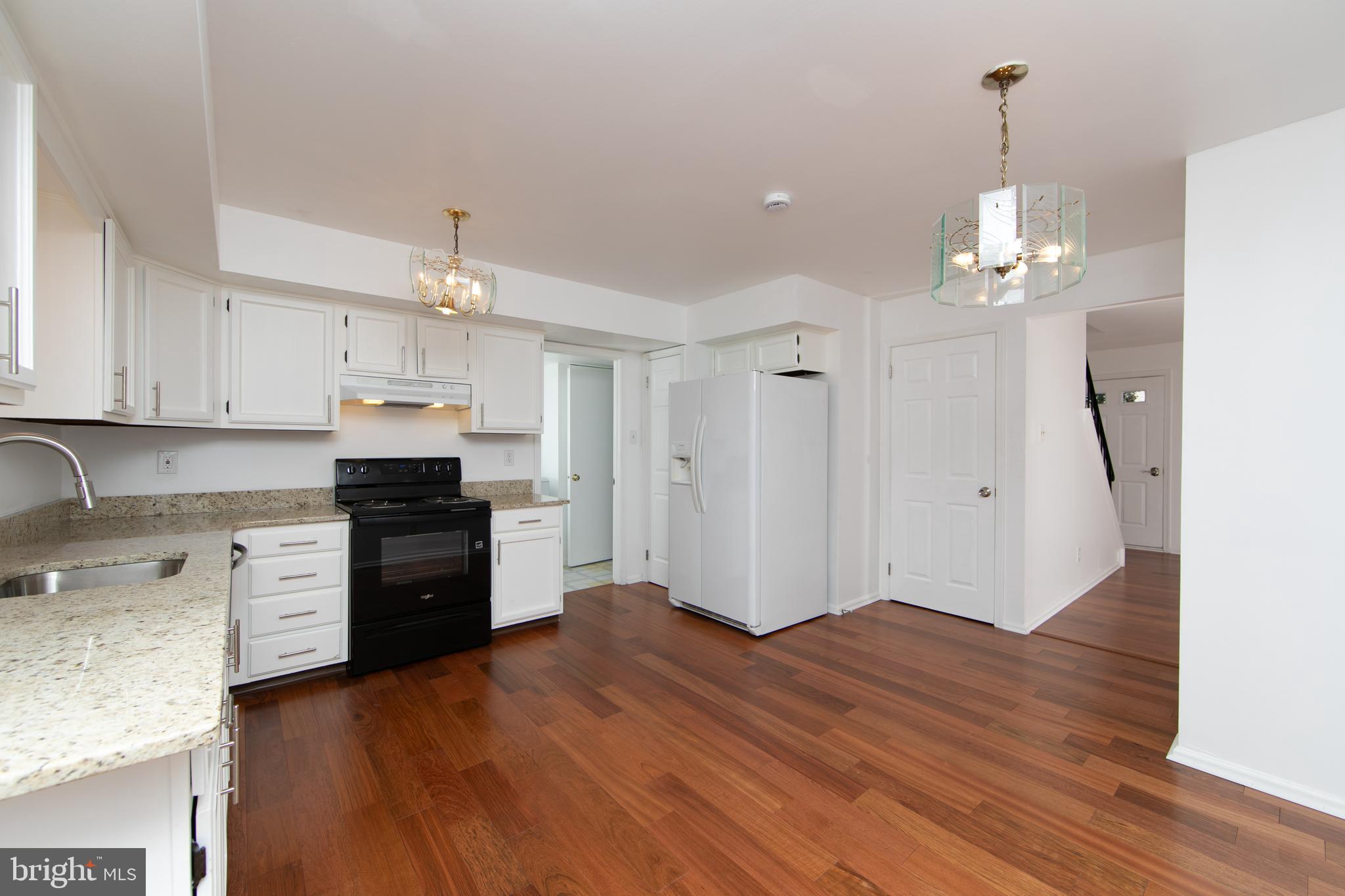 3007 Rampart Road Bensalem, PA 19020 - Photo 14 of 48 a kitchen with granite countertop a refrigerator oven a sink dishwasher and white cabinets with wooden floor