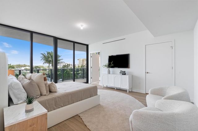 a living room with furniture a flat screen tv and a floor to ceiling window