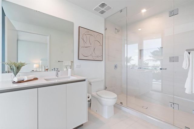 a bathroom with a shower sink vanity mirror and toilet