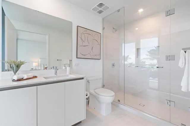 a bathroom with a shower sink vanity mirror and toilet