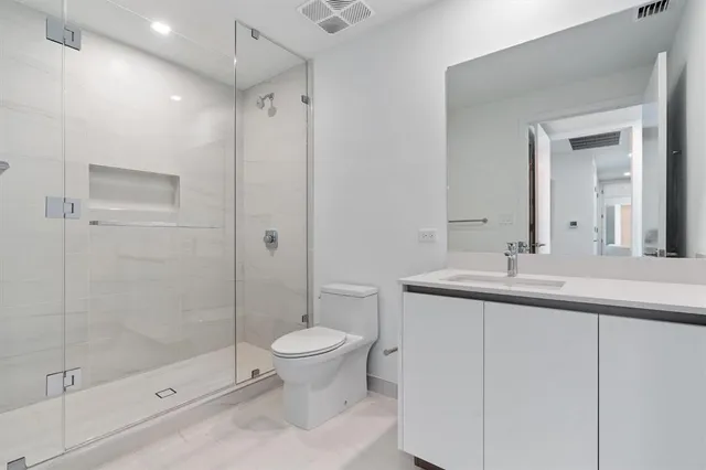 a bathroom with a shower sink vanity and toilet