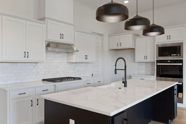 a kitchen with stainless steel appliances a sink a stove a microwave and cabinets