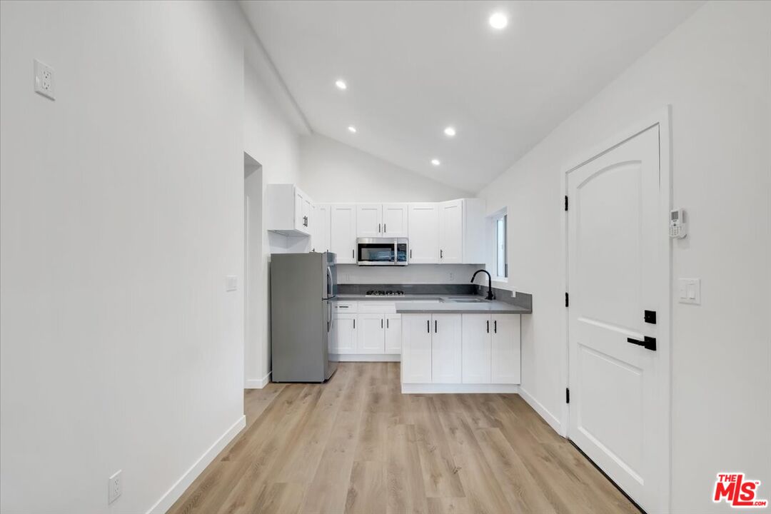 7421 Amigo Avenue Reseda, CA 91335 - Photo 3 of 10 a kitchen with stainless steel appliances a refrigerator sink and white cabinets