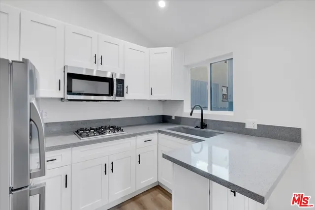 a kitchen with granite countertop a sink stove top oven and cabinets
