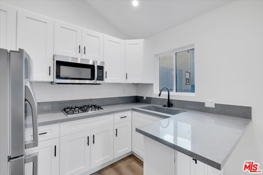 7421 Amigo Avenue Reseda, CA 91335 - Photo 6 of 10 a kitchen with granite countertop a sink stove top oven and cabinets
