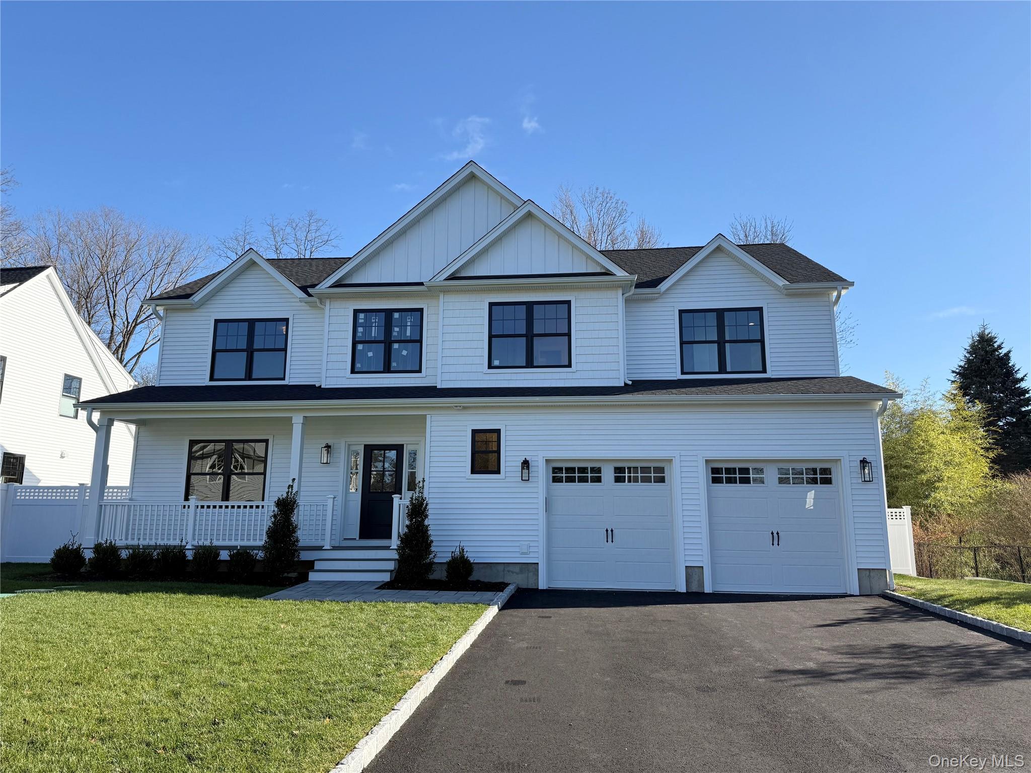 View of front facade featuring covered porch, driveway, board and batten siding, and an attached garage