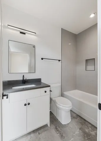 a bathroom with a granite countertop toilet a sink and a mirror