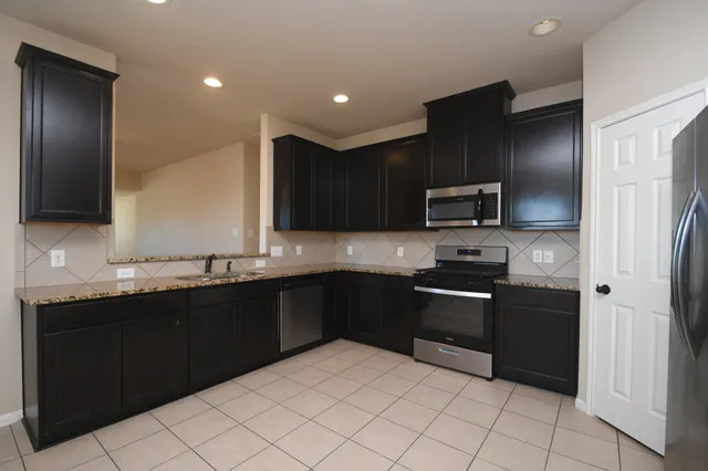 a kitchen with stainless steel appliances granite countertop a refrigerator and a sink