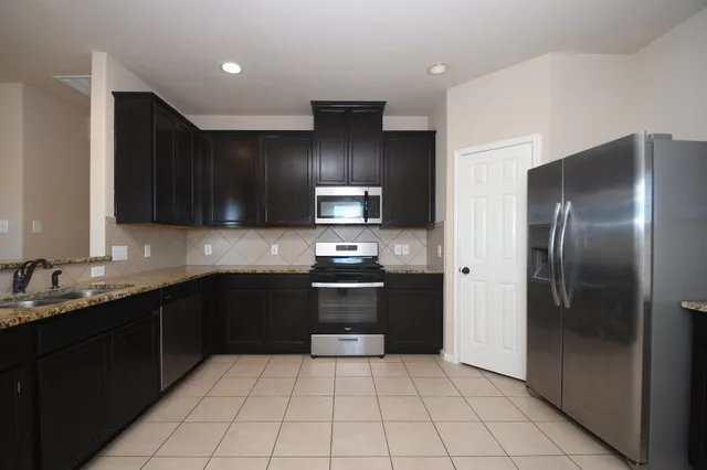 a kitchen with stainless steel appliances granite countertop a refrigerator and a sink