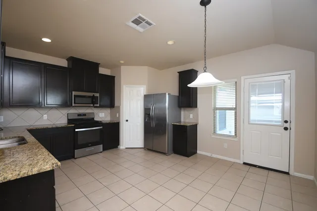a kitchen with stainless steel appliances granite countertop a refrigerator and a sink