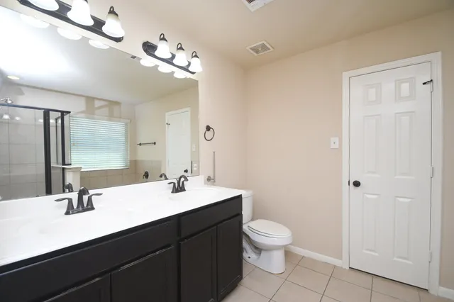 a bathroom with a double vanity sink a toilet and a mirror