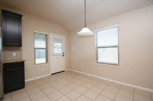 a view of an empty room with window and cabinet