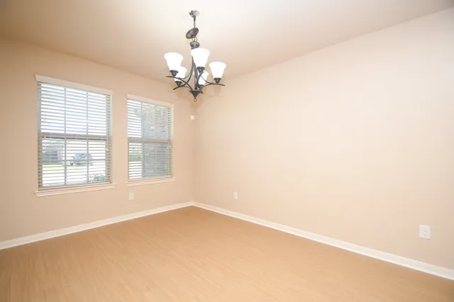 an empty room with a chandelier fan and windows