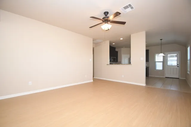 an empty room with a chandelier fan and windows