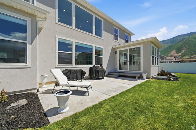 1165 West Union Bench Drive Mapleton, UT 84664 - Photo 57 of 61 Expansive backyard featuring a manicured lawn, concrete patio, and a sunroom with sliding glass doors