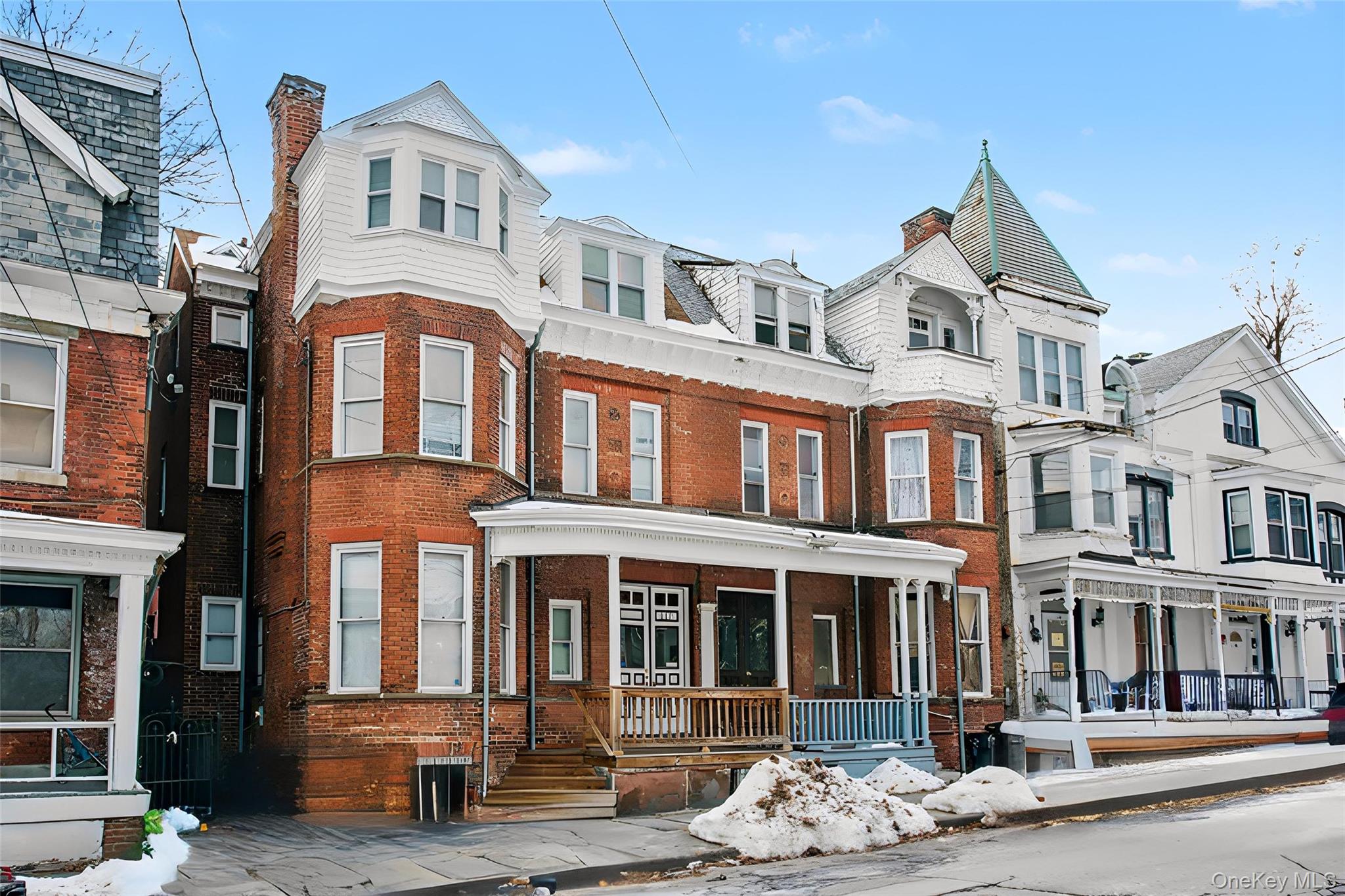 Victorian house with a residential view, brick siding, and covered porch