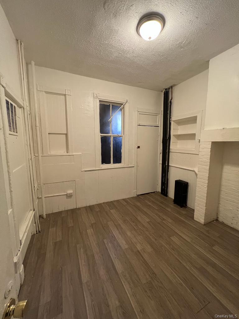 119 Chambers Street Newburgh, NY 12550 - Photo 14 of 18 an empty room with wooden floor fireplace and windows