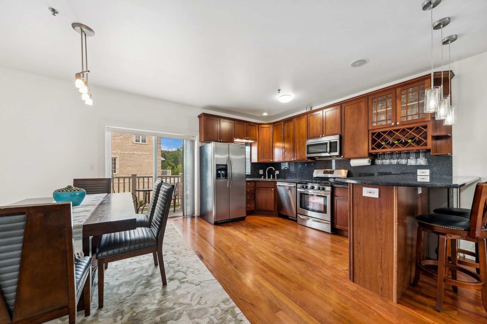 183 East River Road, Unit D2 Des Plaines, IL 60016 - Photo 8 of 42 a kitchen with stainless steel appliances kitchen island granite countertop a refrigerator a stove a sink a dining table and chairs with wooden floor
