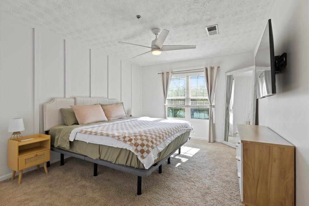 970 Sidney Marcus Boulevard Northeast, Unit 2408 Atlanta, GA 30324 - Photo 13 of 27 a spacious bedroom with a bed and wooden floor