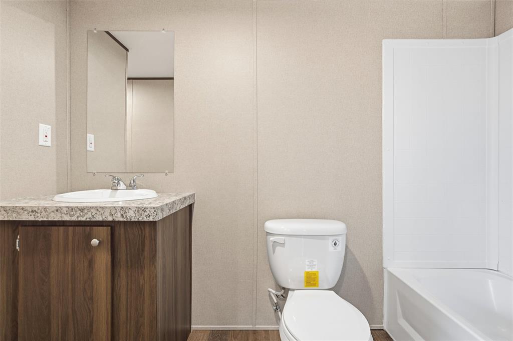 618 East 6th Street, Unit B Blum, TX 76627 - Photo 14 of 24 a bathroom with a granite countertop toilet sink and mirror