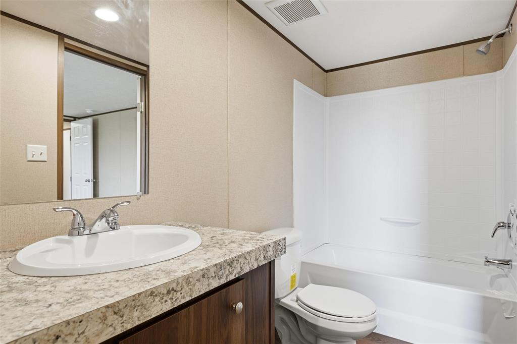 618 East 6th Street, Unit B Blum, TX 76627 - Photo 15 of 24 a bathroom with a granite countertop sink a toilet and shower