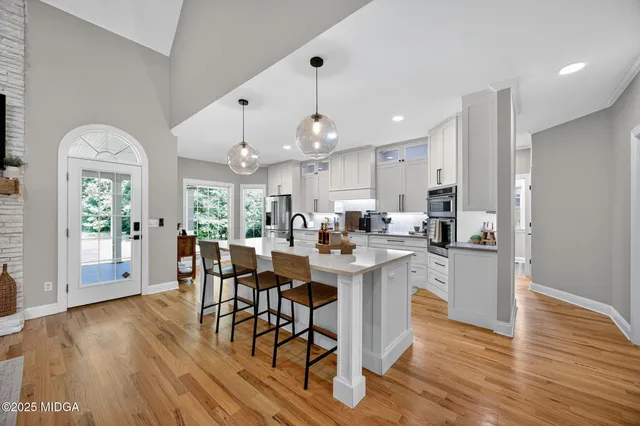 a kitchen with stainless steel appliances a dining table chairs stove and cabinets