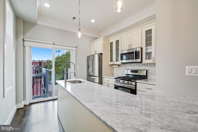 a large kitchen with kitchen island a large counter top space a sink stainless steel appliances and cabinets