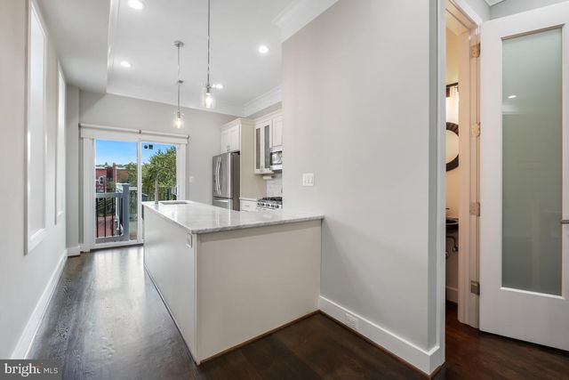 a kitchen with stainless steel appliances granite countertop a refrigerator a sink dishwasher a stove and a dining table with wooden floor