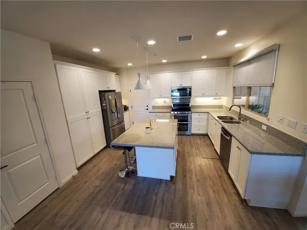 a kitchen with a sink appliances and wooden floor