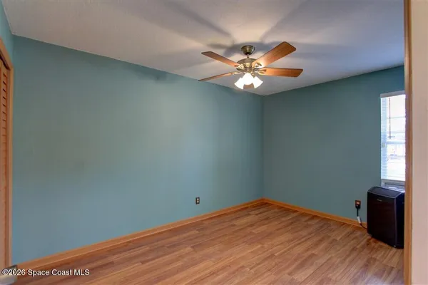 a view of an empty room with window and wooden floor