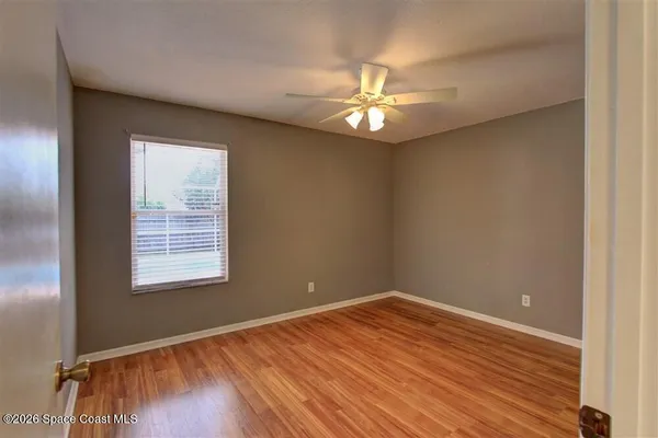 an empty room with wooden floor fan and windows