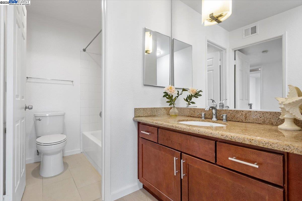 1318 B Street, Unit 314 Hayward, CA 94541 - Photo 16 of 20 a bathroom with a granite countertop sink a toilet and a mirror