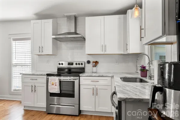 a kitchen with stainless steel appliances granite countertop a stove and white cabinets