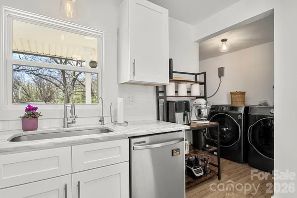 a view of a kitchen with a sink dishwasher and a washer dryer