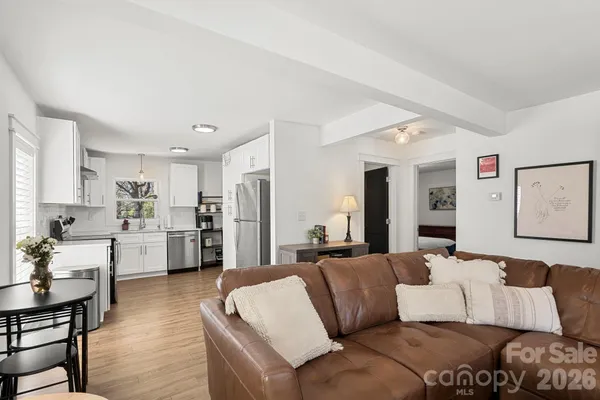 a living room with furniture white refrigerator and kitchen view