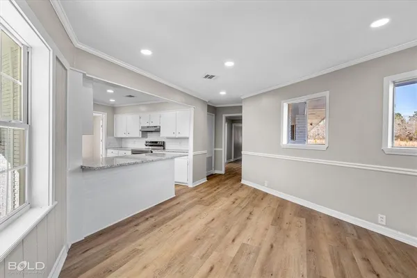 a open kitchen with white cabinets and wooden floor
