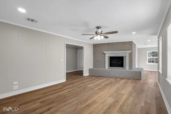 a view of an empty room with wooden floor and fireplace