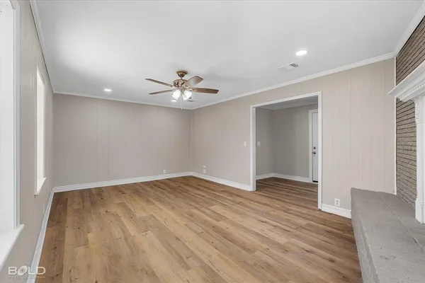 an empty room with wooden floor and chandelier fan