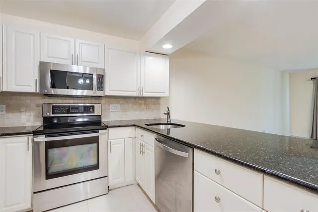 a kitchen with granite countertop white cabinets and stainless steel appliances