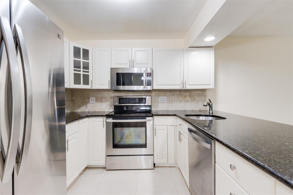 3000 Northeast 5th Terrace, Unit 110A Wilton Manors, FL 33334 - Photo 8 of 30 a kitchen with stainless steel appliances granite countertop a stove a sink and a refrigerator