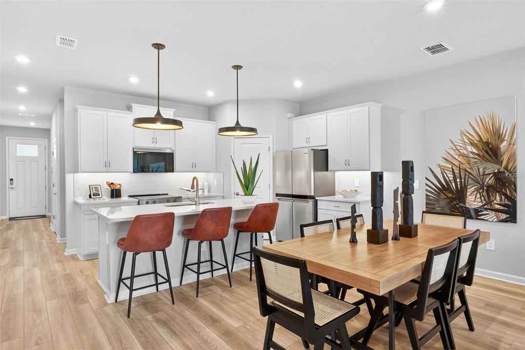 8846 Ginko Run Parrish, FL 34219 - Photo 4 of 24 a kitchen with a dining table chairs and wooden floor