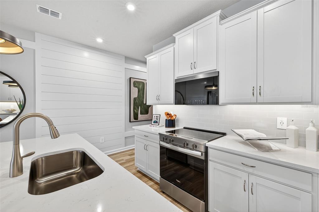 8846 Ginko Run Parrish, FL 34219 - Photo 5 of 24 a kitchen with white cabinets and stainless steel appliances