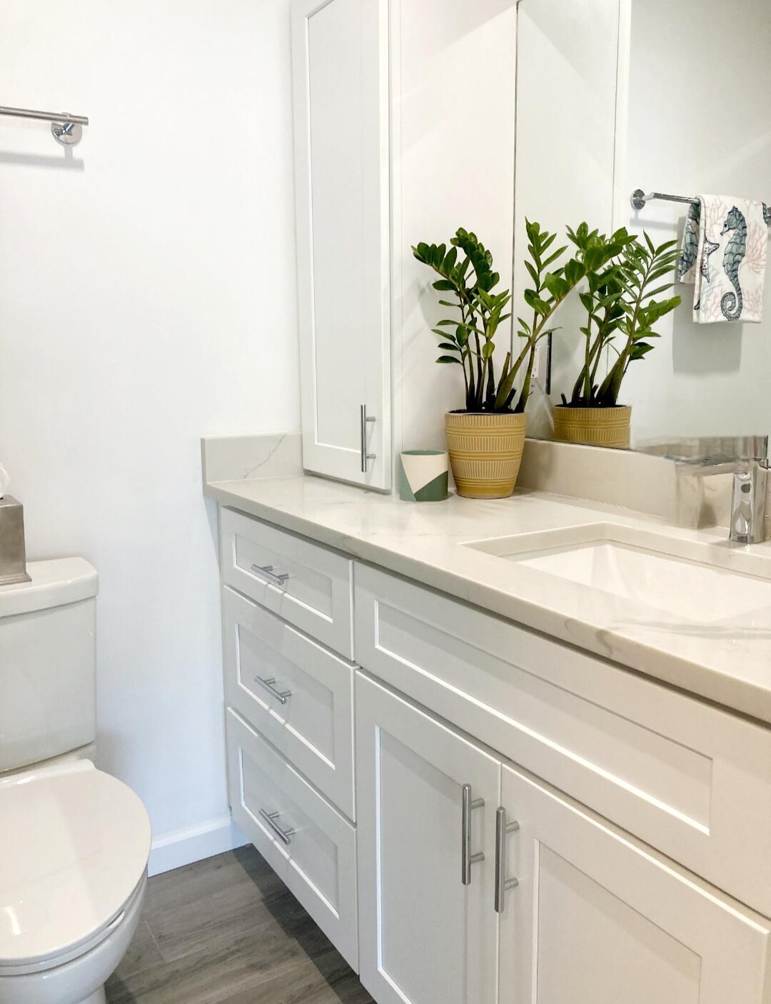 1155 South Drive Circle, Unit A Delray Beach, FL 33445 - Photo 15 of 21 a bathroom with a granite countertop toilet a sink and a mirror