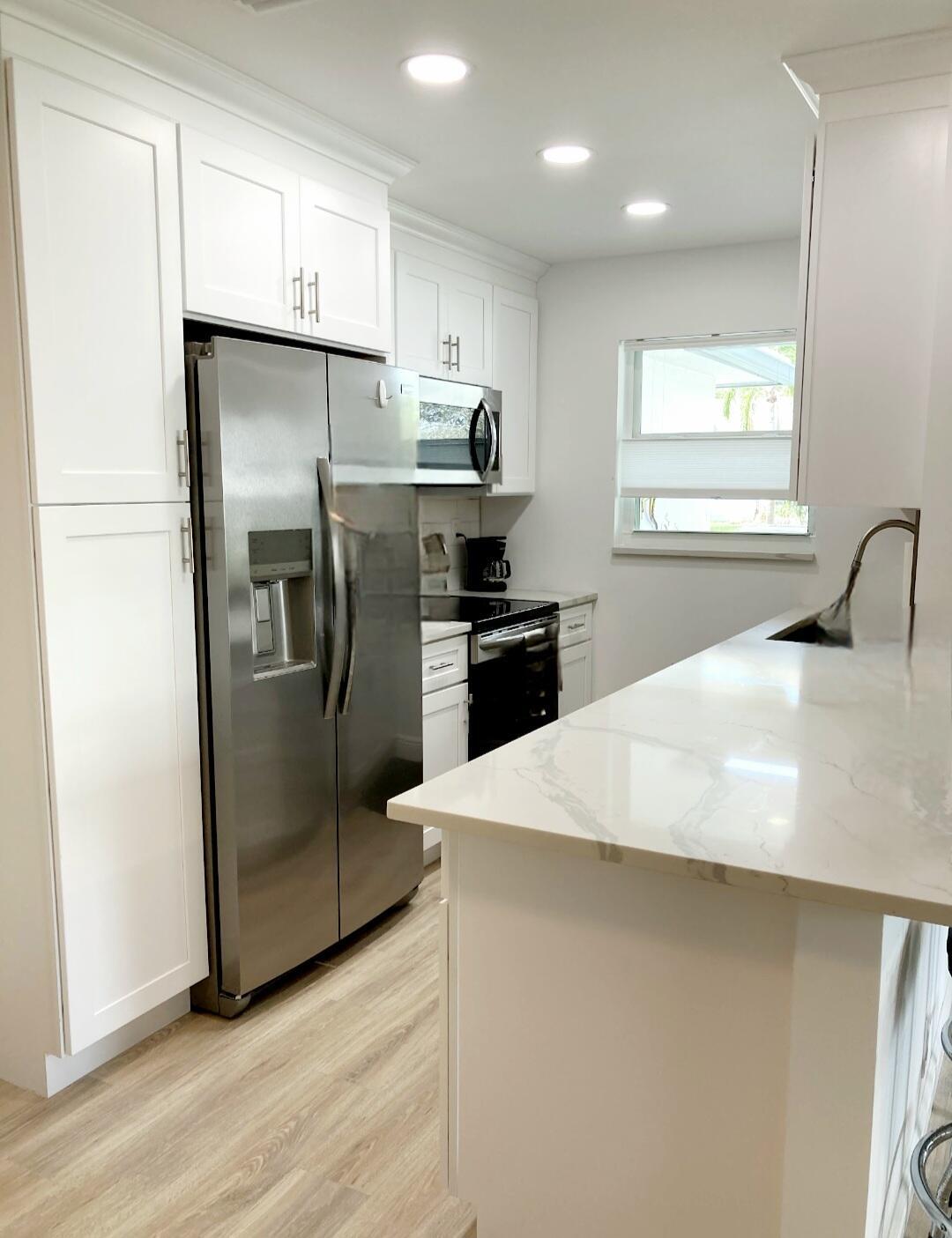 1155 South Drive Circle, Unit A Delray Beach, FL 33445 - Photo 9 of 21 a kitchen with stainless steel appliances a refrigerator sink and microwave