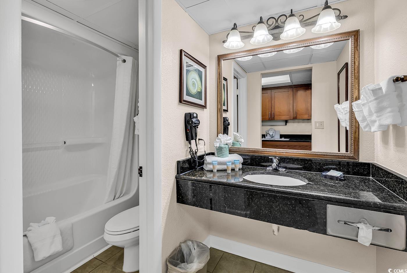1202 North Ocean Boulevard, Unit 310 Myrtle Beach, SC 29577 - Photo 11 of 29 Ensuite bathroom featuring shower / bath combo with shower curtain, tile patterned flooring, vanity, and a textured wall