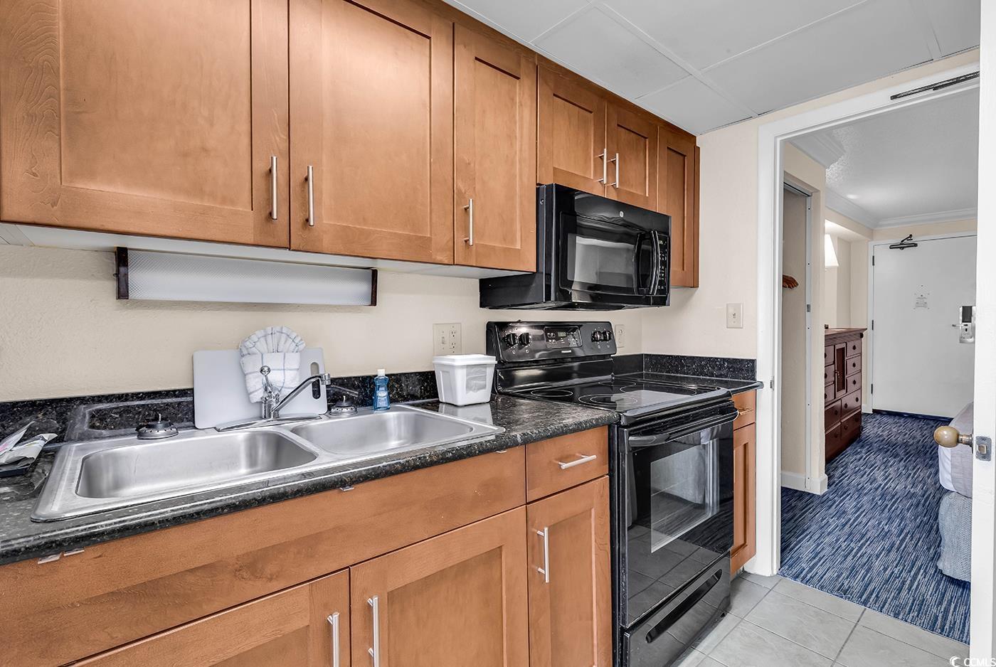 1202 North Ocean Boulevard, Unit 310 Myrtle Beach, SC 29577 - Photo 9 of 29 Kitchen with electric range, brown cabinetry, light tile patterned flooring, and dark stone counters