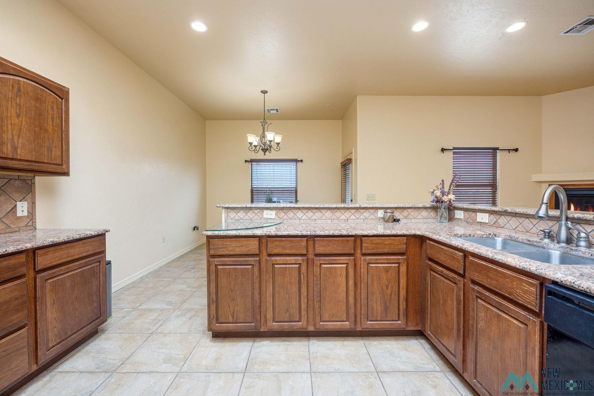 3884 Adriatic Road Las Cruces, NM 88012 - Photo 18 of 45 Kitchen featuring tile flooring, wood-finish cabinetry, granite-style countertops, and a double basin sink