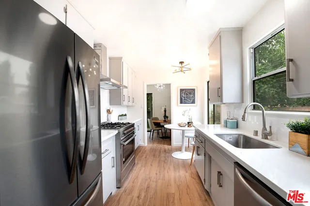 a kitchen with stainless steel appliances a white stove and white cabinets