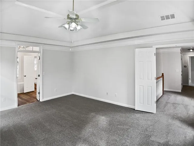 an empty room with a chandelier fan and windows